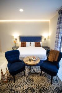a hotel room with a bed and two chairs and a table at Plazuela del Carbón Suites in Cádiz