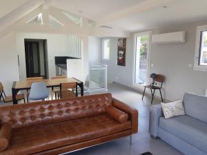 a living room with a brown leather couch and a table at Appartement Terrasses in Sévrier