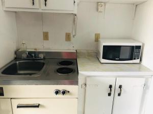 a small kitchen with a microwave and a sink at Manor Motel in Southampton