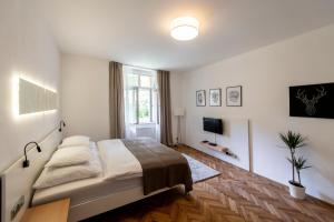 a white bedroom with a bed and a tv at Apartment Slavikova 11 in Prague