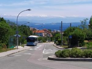 a bus driving down a street with a view of the ocean at ASTREA in Rijeka