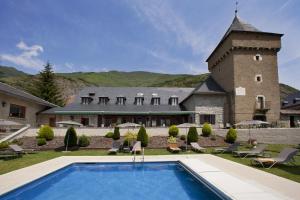 a house with a swimming pool in front of a building at Parador de Artíes in Arties