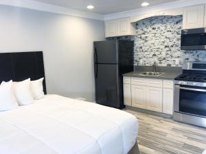 a bedroom with a white bed and a black refrigerator at Crystal Lodge Motel in Ventura