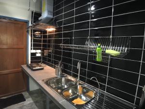 a kitchen with a sink and a black tiled wall at 8th House @ center of Chiangmai old town in Chiang Mai +162 photos