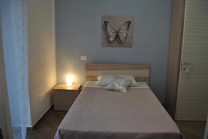 - une chambre dotée d'un lit avec une photo de papillon sur le mur dans l'établissement La Triade affittacamere, à Syracuse
