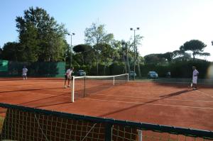 a group of people playing tennis on a tennis court at Cosmopolitan Golf & Beach Resort in Tirrenia