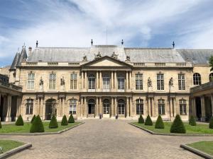 un grand bâtiment avec une cour en face dans l'établissement Pavillon Marais, à Paris