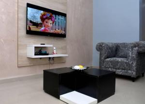 a living room with a couch and a tv on a wall at Onimz Apartments in Abuja