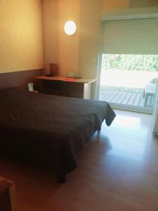 um quarto com uma cama e uma porta para uma varanda em Hotel Les Gravades Ussel em Ussel