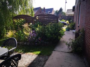 un jardín con una valla de madera y flores púrpuras en Gite a la Ferme - Baie de Somme en Saint-Quentin-Lamotte-Croix-au-Bailly