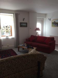 a living room with a red couch and a table at Lower Thura House in Wick