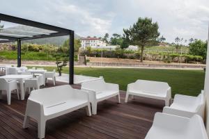 un patio con mesas blancas y sillas en una terraza en INATEL Cerveira Hotel en Vila Nova de Cerveira