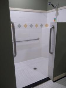 bagno con doccia, servizi igienici e pavimento piastrellato. di Southern Comfort Suites a Mayfield