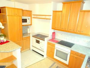 - une cuisine avec des placards en bois et des appareils blancs dans l'établissement Appartement Christine, à Grossarl