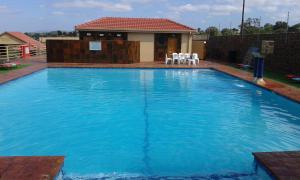 a large blue swimming pool with two white chairs in it at Jericho Hotel and Conferences in Thohoyandou