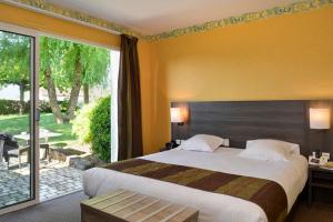 a hotel room with a bed and a large window at Logis Hôtel Restaurant des Châteaux in Azay-le-Rideau