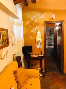 a living room with a yellow couch and a writing on the wall at Holiday Home La Casetta delle Candele in Montemerano
