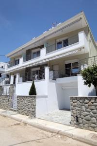a white house with a stone wall at SunsetPeramos in Nea Peramos