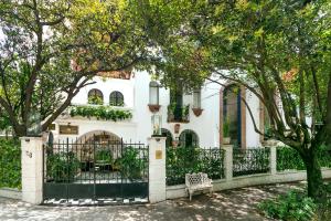 墨西哥城的住宿－Orchid House Polanco，白色的房子,有黑色的栅栏和树木