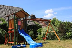 a girl is on a slide on a playground at Przytulny kąt in Białowieża