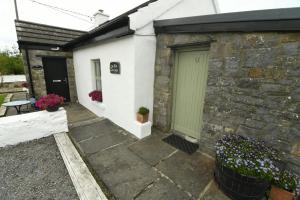 een stenen huis met een groene deur en bloemen bij The Old Cottage in Doolin