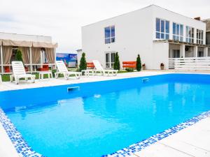 a swimming pool with chairs and a house in the background at EUROLINE HOTEL ODESSA in Odesa