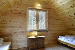 a bedroom in a log cabin with a window at Sosenka 6 - całoroczne domki rekreacyjne in Milicz