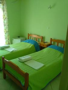 2 camas en una habitación con sábanas verdes en To Giouli en Volos