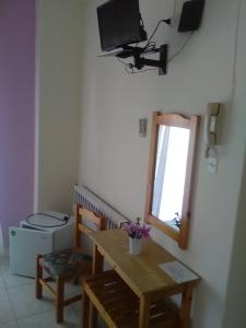 uma sala de estar com uma mesa e uma televisão na parede em To Giouli em Volos