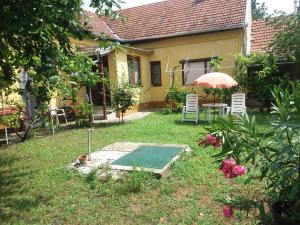 a garden with a table and chairs and an umbrella at Hársfák in Mezőkovácsháza