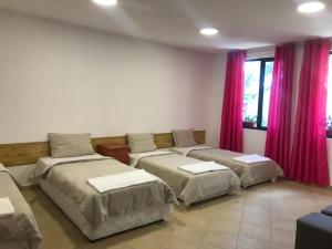 a room with three beds and a couch with pink curtains at Нощувки Шумен in Shumen