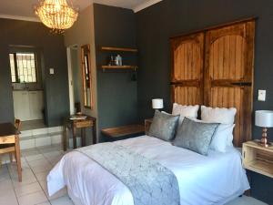 a bedroom with a white bed with a wooden headboard at Green Hollow Self catering in Knysna