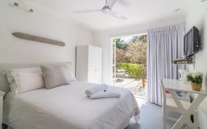 a white bedroom with a bed and a desk and a window at Green Park Manor in Johannesburg