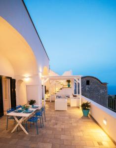 Un patio con mesas y sillas en un balcón. en Villa Marilisa, en Conca dei Marini