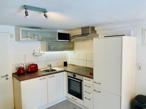 una pequeña cocina con armarios blancos y nevera. en The Panamericana, en Riedstadt