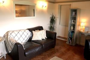 um sofá de couro numa sala de estar com um espelho em Mortimer Trail B and B em Aymestrey