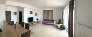 a living room with a purple couch and a tv at Hanul Piratilor Promenada Apartament in Mamaia Nord