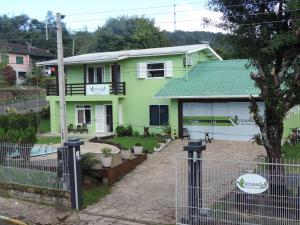 una casa verde con una valla delante en Pousada Três Coroas, en Três Coroas