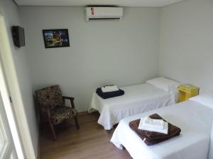 una habitación de hotel con 2 camas y una silla en Pousada Três Coroas, en Três Coroas
