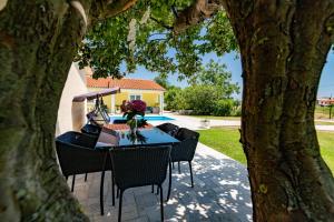 a table and chairs sitting under a tree at Holiday house Mary in Barban