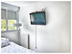 a tv hanging on a wall in a bedroom at Modern & Chic Appartement- GoodVibes Paris in Gonesse