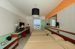 1 dormitorio con 2 camas, TV y sofá en Hotel Vienna, en Cattolica