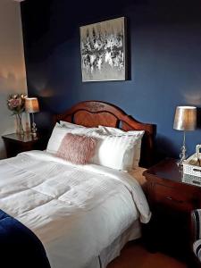 a bedroom with a white bed with a blue wall at Lake Avenue House in Ballyconnell