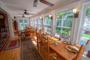 a dining room with a table and chairs and windows at Phineas Swann Inn & Spa in Montgomery Center