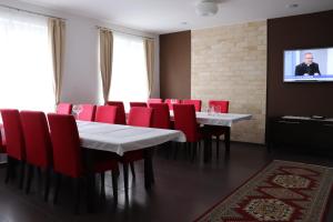 a dining room with red chairs and a table and a tv at Villa Žakýl in Banská Štiavnica