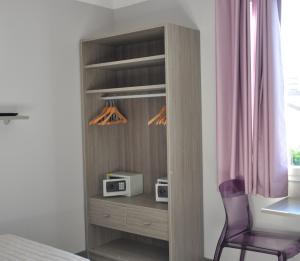 a wooden closet with a microwave and a chair at Résidence Aragon in Juan-les-Pins