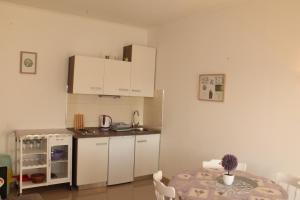 a kitchen with a table and white cabinets and a table and chairs at Knezovic Apartments in Podstrana