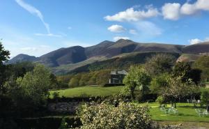 una casa en un campo con montañas en el fondo en The Heights Hotel en Keswick