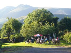 a group of people sitting under an umbrella in the grass at The Heights Hotel in Keswick