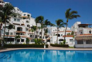 una piscina frente a un edificio con palmeras en Condominio Puerto Las Hadas, en Manzanillo